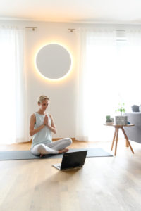 Woman 40+ practices yoga at home with notebook. Online yoga class. Woman 40+ practices yoga at home with notebook. Online yoga class.